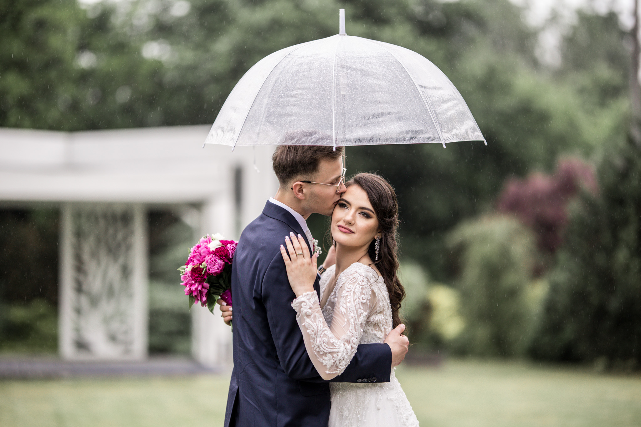 Sesja ślubna w deszczu pod przezroczystym parasolem